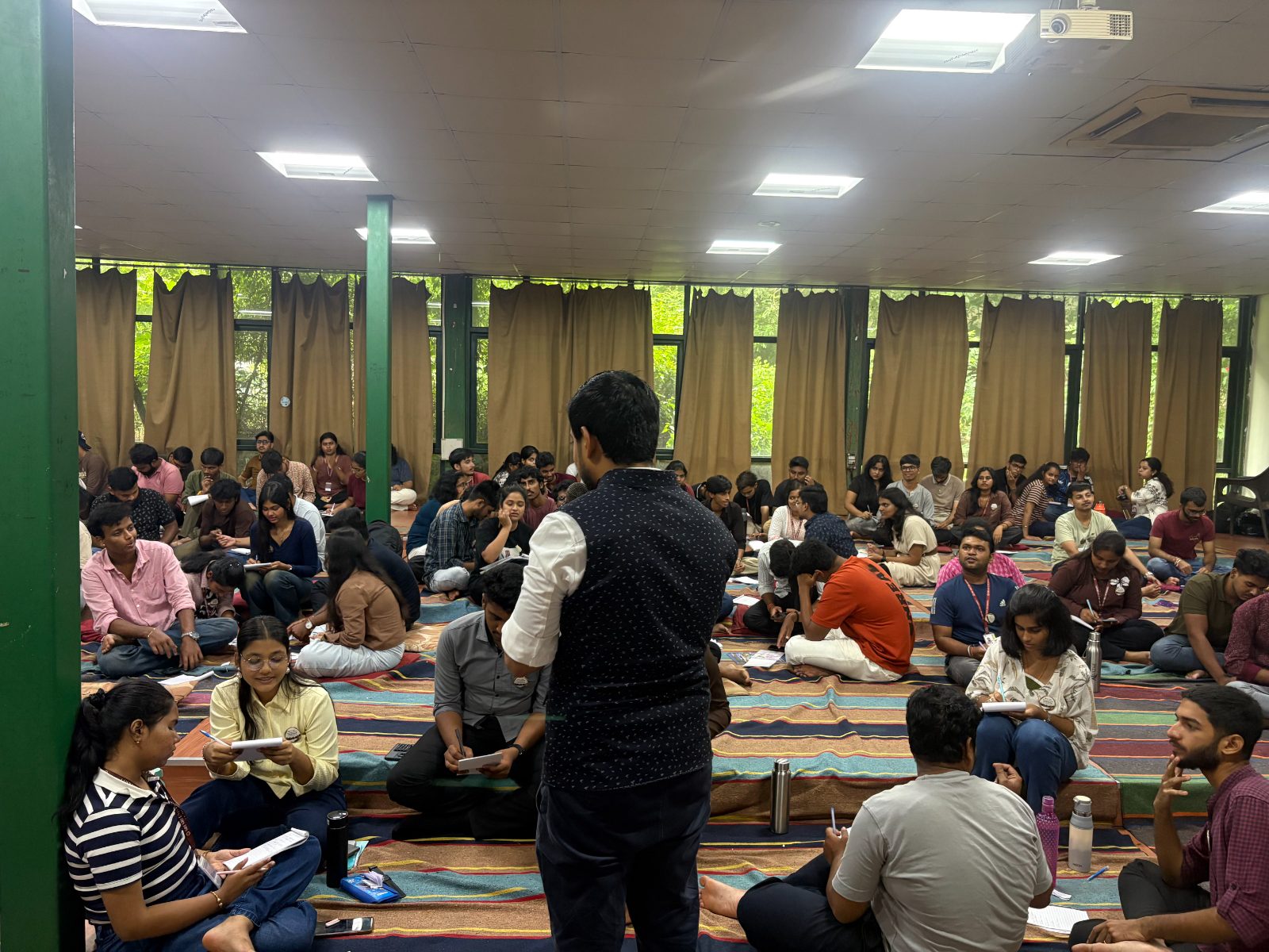 A facilitator addressing participants seated on floor mats